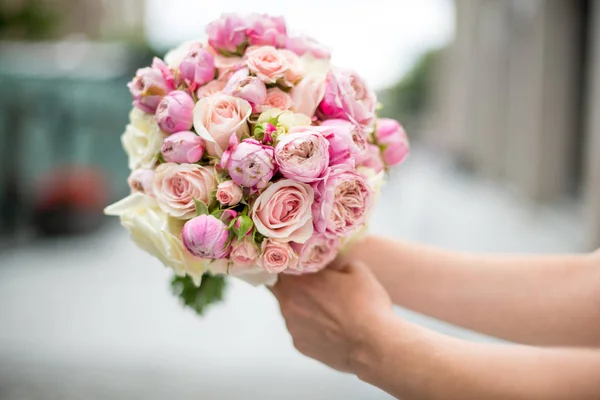 Un bouquet da sposa di rose e peonie nelle mani della sposa. primo piano. Su uno sfondo sfocato — Foto Stock