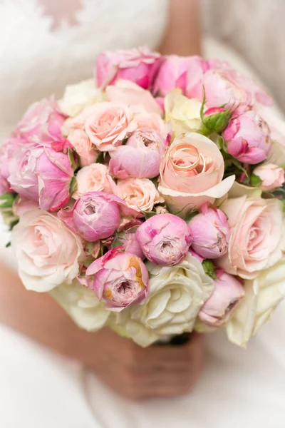 Un bouquet da sposa di rose e peonie nelle mani della sposa. primo piano. Su uno sfondo sfocato — Foto Stock