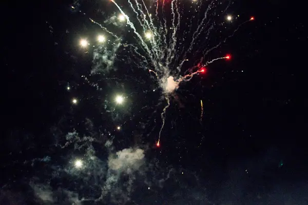 A few volleys of festive fireworks in the night sky, red-yellow. — Stock Photo, Image