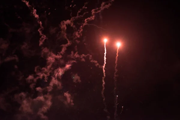 Een paar volleys van feestelijke vuurwerk in de nachtelijke hemel, rood-geel. — Stockfoto