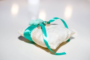 Beyaz yastık üzerinde altın alyans çifti.