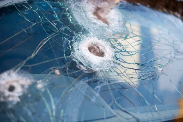 Bullet hole on a car windshield. Car window after a raid has a bullet hole. Broken glass. Bullet holes in a front windshield. Broken Windshield.