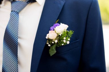 Damat unsuru mavi bir kravat ve ceketinin cebinde yaka çiçeğiyle.