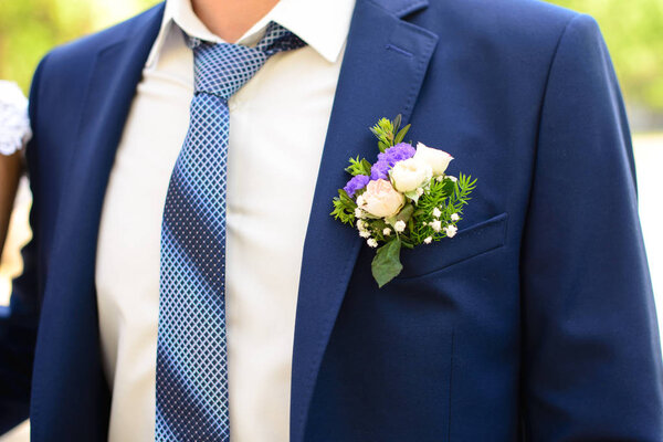 The element of the grooms blue suit with a blue necktie and Boutonniere in his jacket pocket