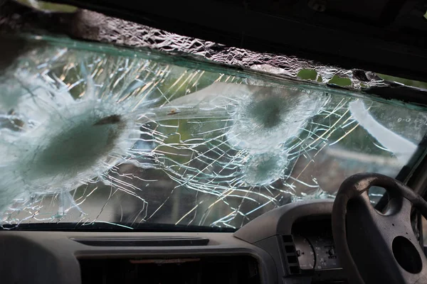 Bullet hole on a car windshield. Car window after a raid has a bullet hole. Broken glass. Bullet holes in a front windshield. Broken Windshield