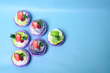 Krem şantili kekler çikolatalı gofret, çilek, mavi arka planda badem kurabiyesi. Menü ya da şekerleme kataloğu için resim. metin için boşluk ile