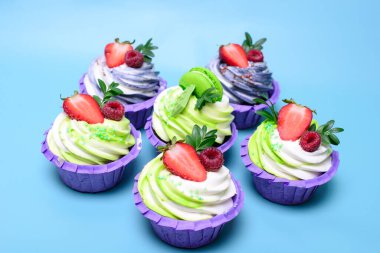 Krem şantili kekler çikolatalı gofret, çilek, mavi arka planda badem kurabiyesi. Menü ya da şekerleme kataloğu için resim. metin için boşluk ile