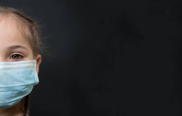 Kırmızı gözlü, siyah arka planda tıbbi maskesi olan yarım suratlı kız, kopyalama alanı. Koronavirüs karantinasında izole edilmiş insanların konsepti
