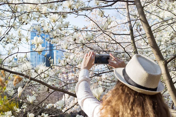 Girl takes pictures of flowers and building