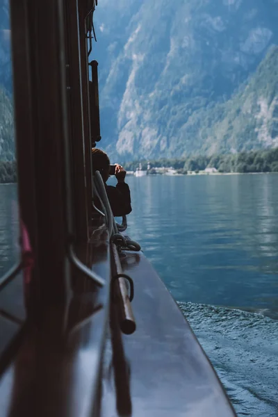 View from a wooden boat with windows on a beautiful lake, people take a photo. Bavaria, Germany, Konigssee