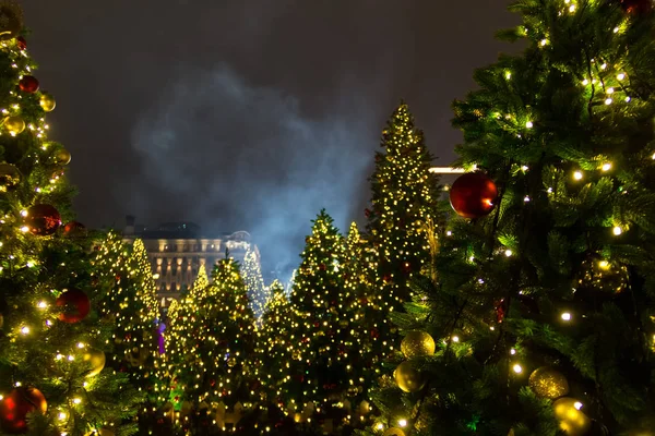 Weihnachtsbäume Hintergrund und Weihnachtsschmuck mit Schnee, verschwommen, funkelnd, leuchtend am Abend. Frohes neues Jahr und Weihnachtsthema — Stockfoto
