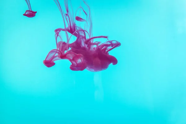 purple paint drops in water. Ink swirling underwater.