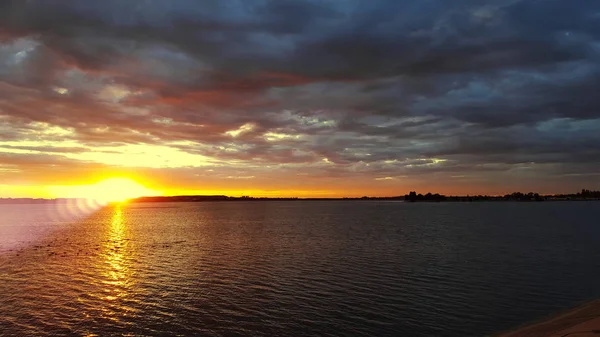 Atardecer naranja sobre un lago europeo, cielo de nubes azules, escena dramática de colores — Foto de Stock