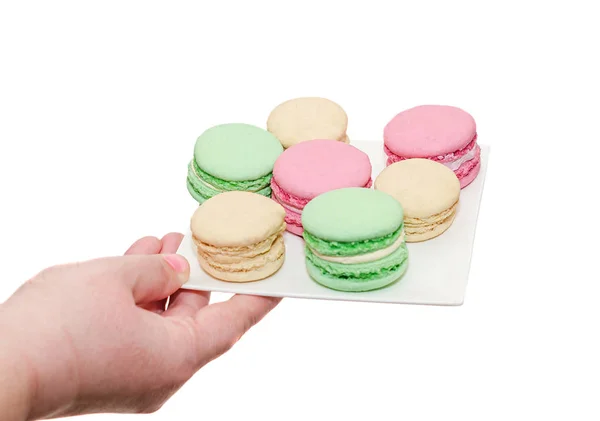 Mano de mujer sosteniendo un plato blanco con macarrones dulces de colores — Foto de Stock