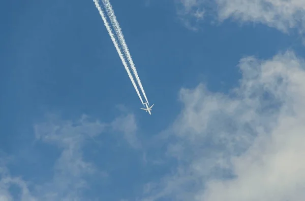 Літак з реакційною стежкою, що літає над блакитним небом з хмарами — стокове фото