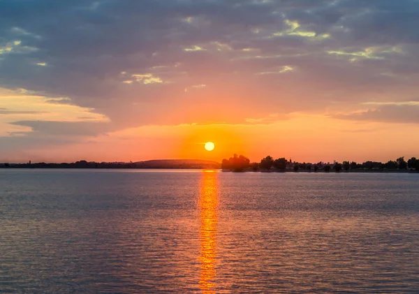 Pôr-do-sol laranja sobre um lago europeu, céu azul nuvens, colorido dramático — Fotografia de Stock