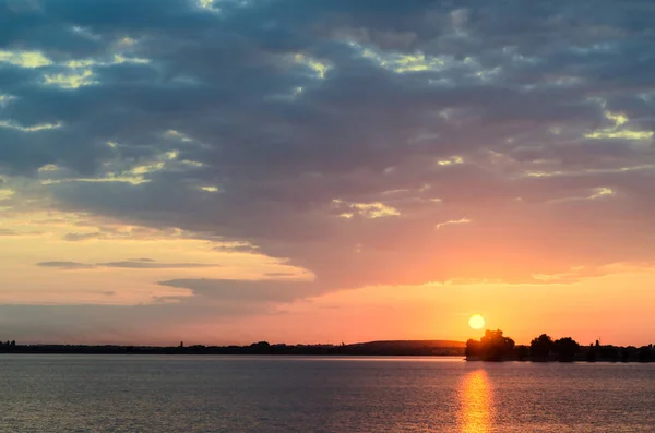 Pôr-do-sol laranja sobre um lago europeu, céu azul nuvens, colorido dramático — Fotografia de Stock