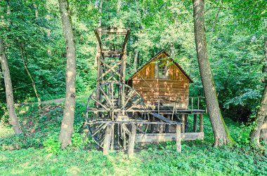 Watermill yakın kadar yeşil orman, vahşi bitki örtüsü, mavi bulutlar gökyüzü