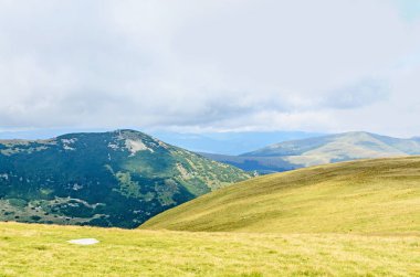 Bulutlar, yeşil çim ve kayalar ile hills Parang dağlarda