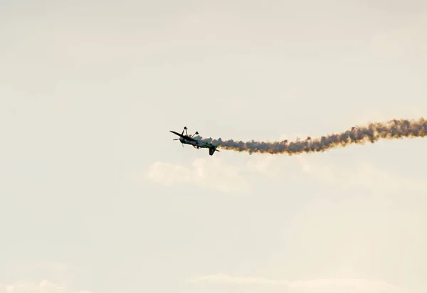 Avião com fumaça colorida traço voando no céu nuvens azuis — Fotografia de Stock