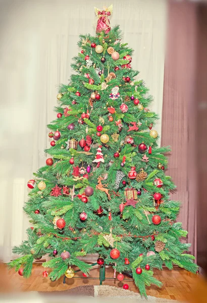 Zelený vánoční strom s mnoha zářivé barevné ornamenty — Stock fotografie
