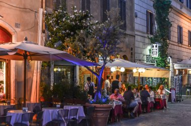 Roma şehrin sokaklarında gecesi. İnsanlar joying restoranlar ve teraces.