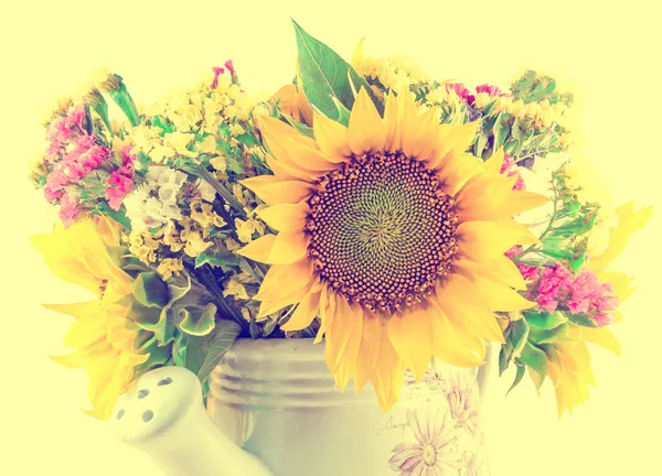 Yellow sunflowers and colored wild flowers in a white sprinkler,