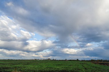 Üzerinde mavi gökyüzü, gökkuşağı renkli yağmurlu bir gün.