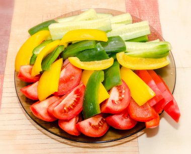 Şeffaf plaka dilimlenmiş kırmızı domates, sarı ve yeşil capsicums ve salatalık ile