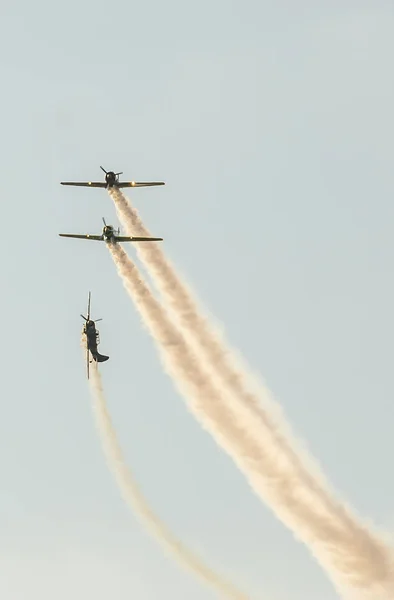 Pilotos de aviones acrobáticos entrenando en el cielo de la ciudad. Avión de color con rastro de humo . — Foto de Stock