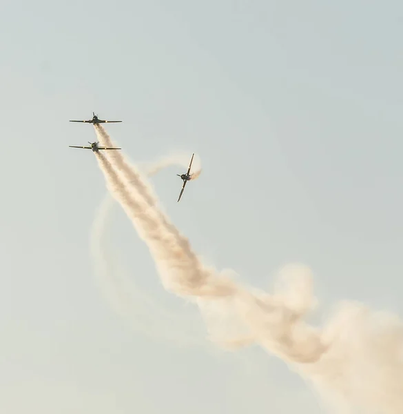 曲技飛行の飛行機のパイロットは、市の上空で訓練。トレースの煙と色の飛行機. — ストック写真