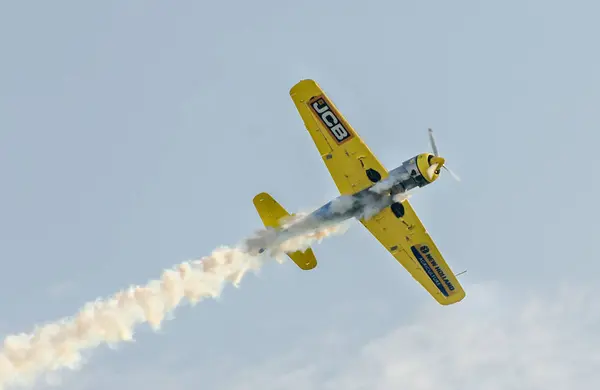 Aerobatic flygplan piloter utbildning i himlen över staden. Färgade flygplan med spår rök. — Stockfoto