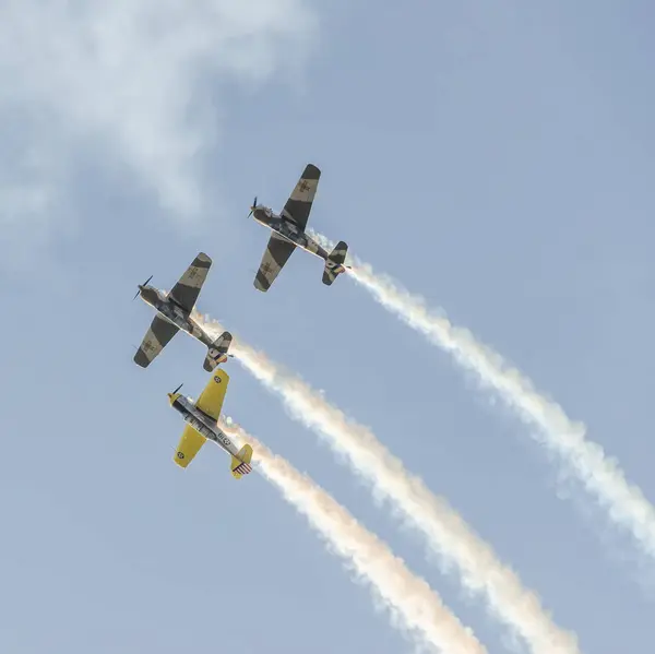 Aerobatic airplane pilots training in the sky of the city. Colored airplane with trace smoke. — Stock Photo, Image