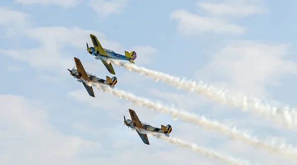 Pilotos de aviones acrobáticos entrenando en el cielo de la ciudad. Avión de color con rastro de humo . — Foto de Stock