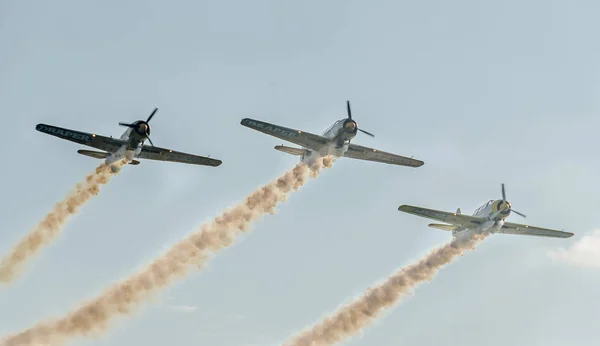 Samolot akrobacyjny pilotów szkolenia na niebie miasta. Kolorowe samolot z śledzenia dymu. — Zdjęcie stockowe
