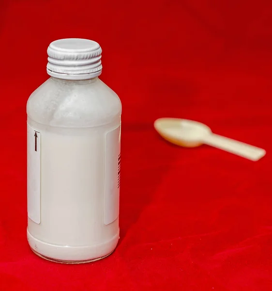Białe butelki z syropem medyczny narkotyków i łyżką małe, czerwone z powrotem — Zdjęcie stockowe