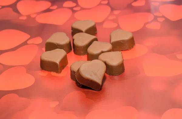 Herzförmige Schokolade, Valentinstag-Bonbons, braun-roter Hintergrund — Stockfoto