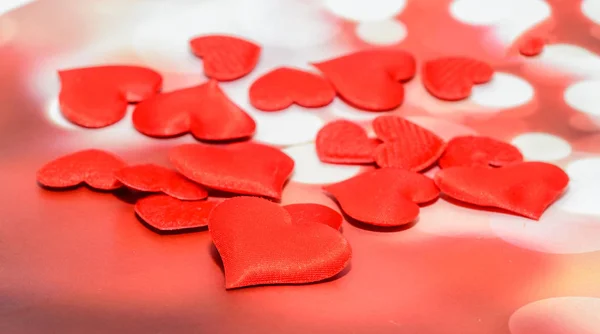 Textil corazones rojos, corazones del día de San Valentín, fondo rojo bokeh . —  Fotos de Stock