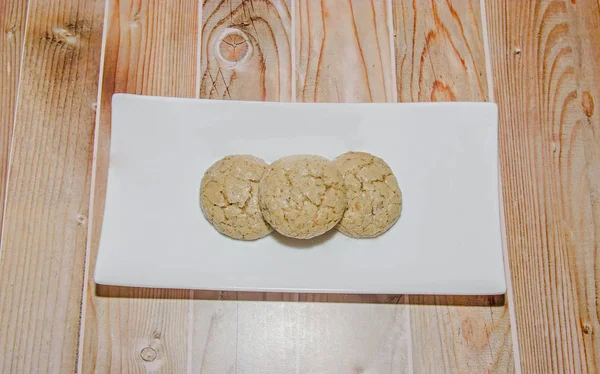 Galletas redondas apiladas en un plato blanco, azúcar en polvo, fondo de madera — Foto de Stock