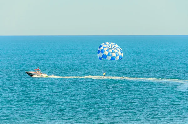 Blue parasail wing pulled by a boat in the sea water, Parasailing