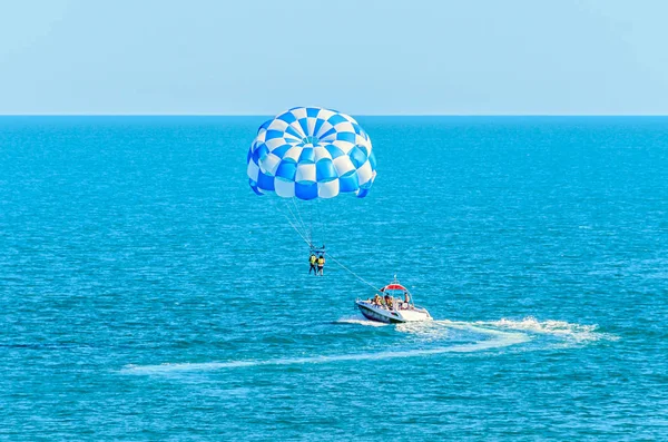 Skrzydło niebieski parasail ciągniętym przez łódź w wodzie morskiej, Parasailing — Zdjęcie stockowe