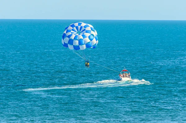 Blå parasittvinge trukket av en båt i havet, Parasailing – stockfoto