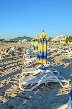 Güneş şemsiyesi, sahil kumu ve yataklar renkli şeritli