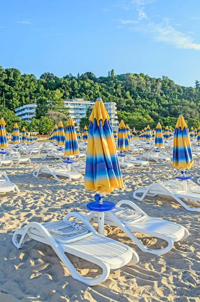 Кольорові роздягнені сонцезахисні парасольки, пляжний пісок і ліжка — стокове фото