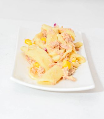 Kırmızı soğan, ton balığı ve Mısır, beyaz tabak izole ile pişmiş makarna