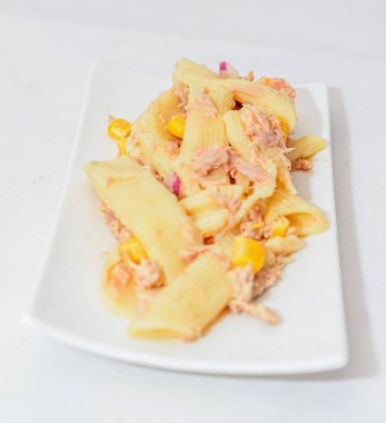 Kırmızı soğan, ton balığı ve Mısır, beyaz tabak izole ile pişmiş makarna