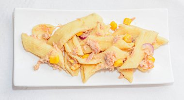 Kırmızı soğan, ton balığı ve Mısır, beyaz tabak izole ile pişmiş makarna