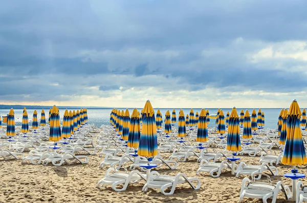 Colored stripped sun umbrellas, golden beach sand and sunbeds