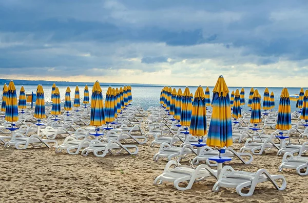 Кольорові роздягнені сонцезахисні парасольки, золотий пляжний пісок і лежаки — стокове фото