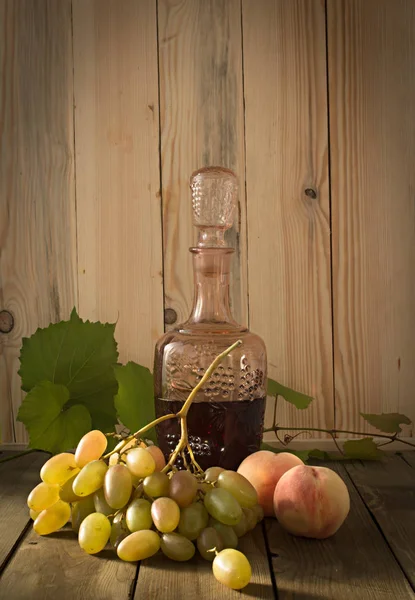 Stilleben med rött vin, vindruvor och persikor — Stockfoto